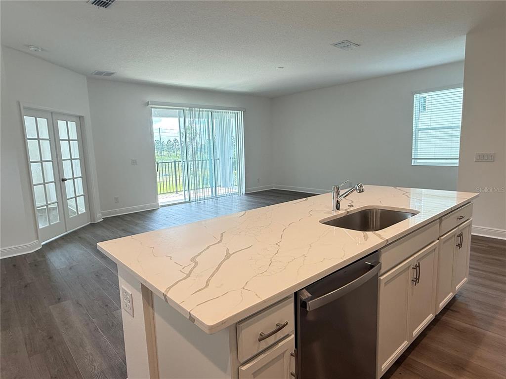A kitchen island with a white marble countertop and sink overlooks an open living area — 7497 CATANIA LOOP, CLERMONT, FL