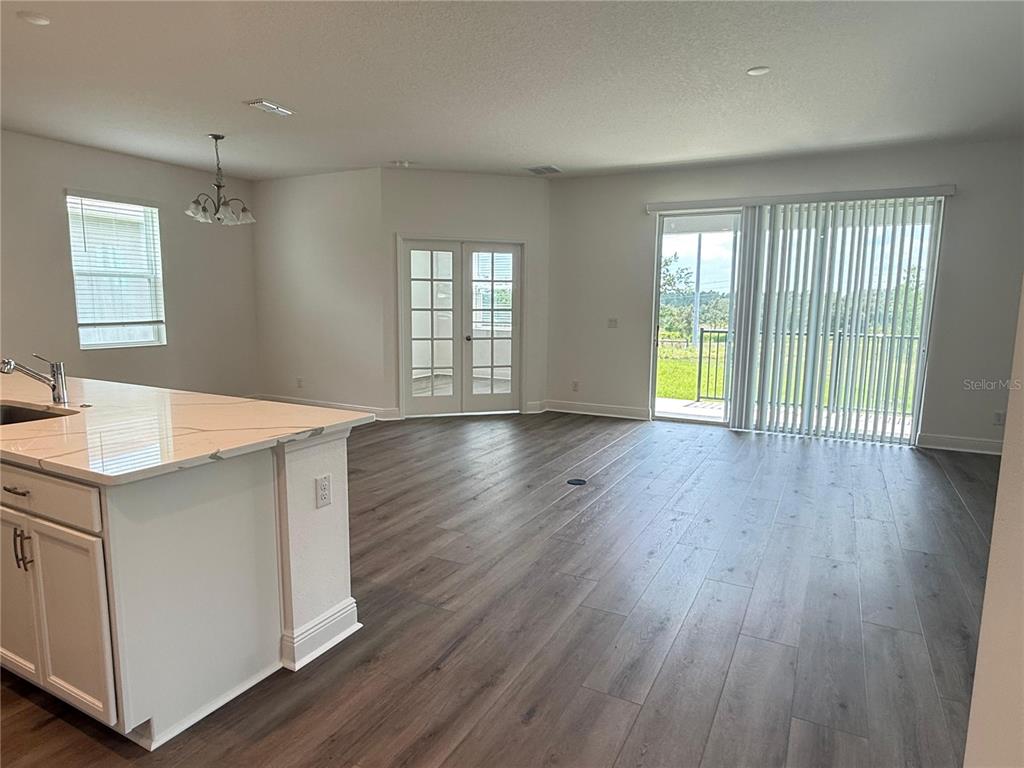 A kitchen island with a marble countertop overlooks an open living area with wood-look flooring — 7497 CATANIA LOOP, CLERMONT, FL