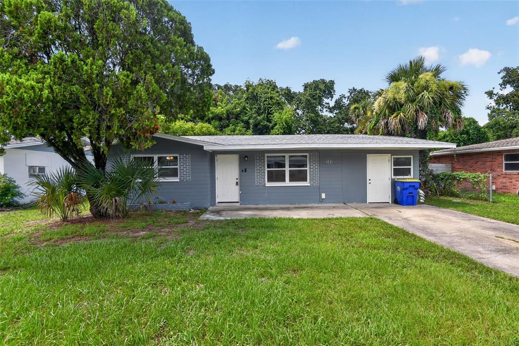 A single-story gray house with a concrete driveway and a large tree in the yard — 305 JOYCE STREET, EDGEWATER, FL