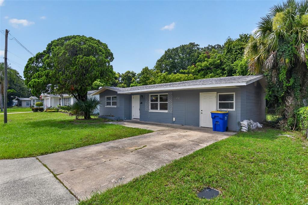 A single-story gray house with a concrete driveway and a blue trash bin outside — 305 JOYCE STREET, EDGEWATER, FL