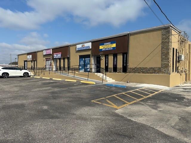 A single-story commercial strip mall with a parking lot and a white car parked outside — 1011 W LANCASTER ROAD, ORLANDO, FL