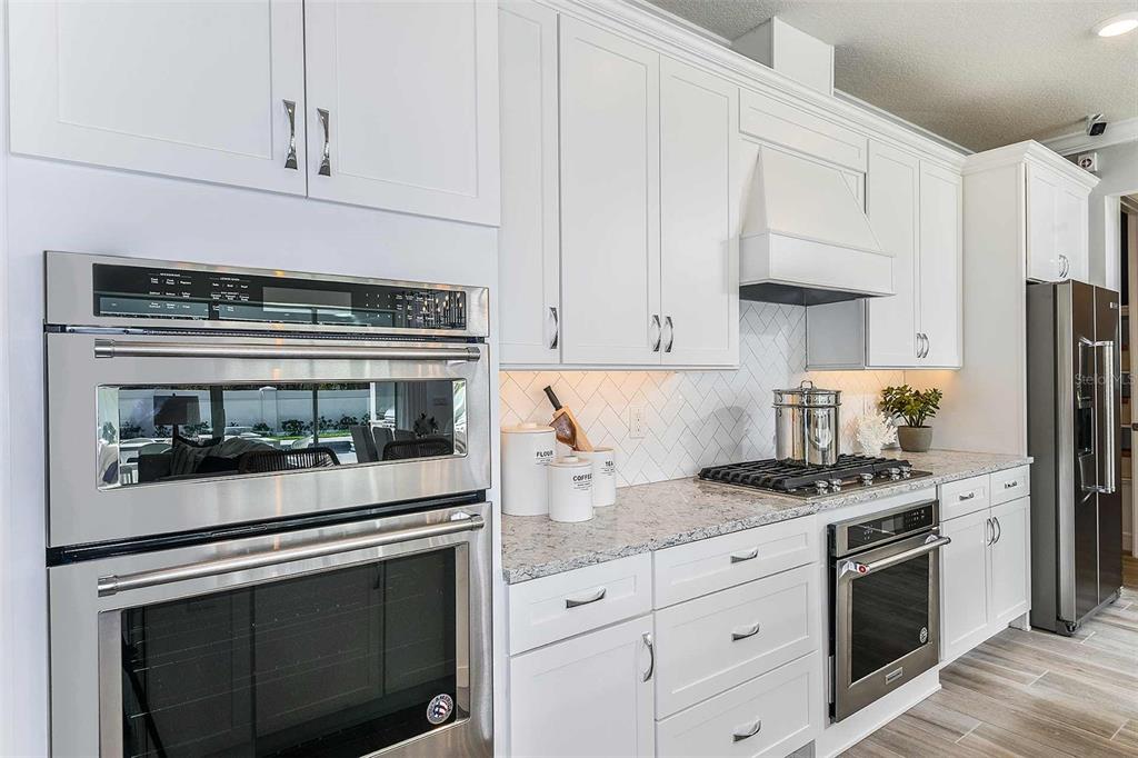 A modern kitchen features white cabinetry, stainless steel appliances, and a light-colored granite countertop — 9030 WANDER TRAIL, MELBOURNE, FL