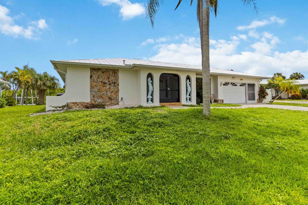 A single-story house with a stone accent wall, arched entryway, and a white garage — 18606 BRIGGS CIRCLE, PORT CHARLOTTE, FL