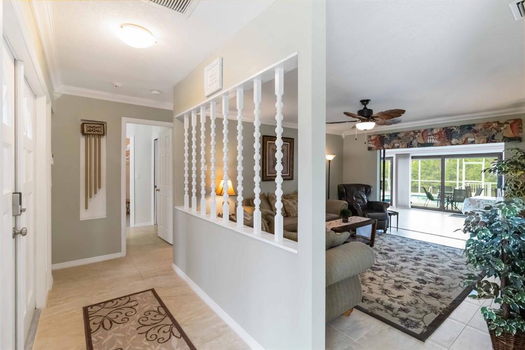 An entryway with tile flooring leads to a living room featuring a decorative spindle partition — 18606 BRIGGS CIRCLE, PORT CHARLOTTE, FL