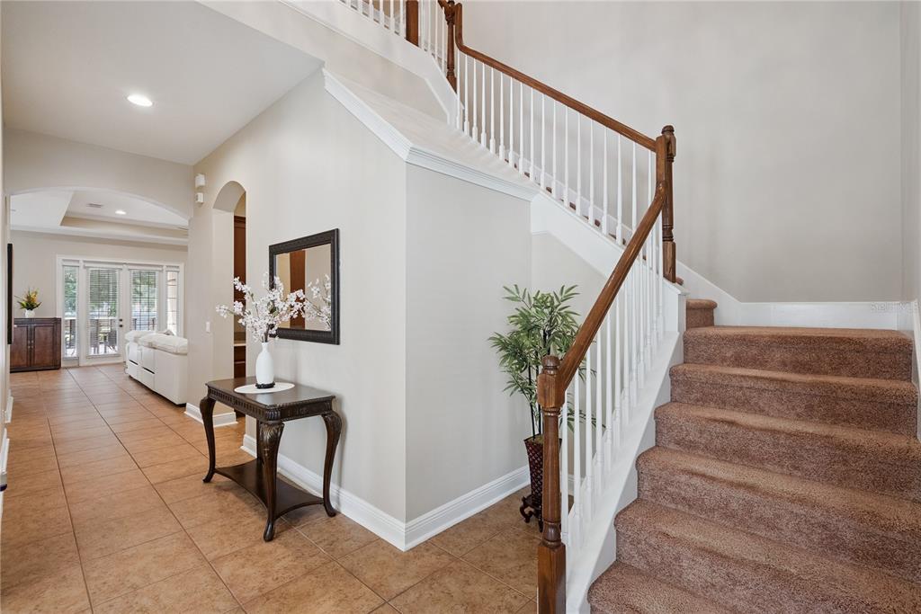 A carpeted staircase with a wooden railing sits beside a hallway with tiled floors — 3600 SIMONTON PLACE, LAKE MARY, FL