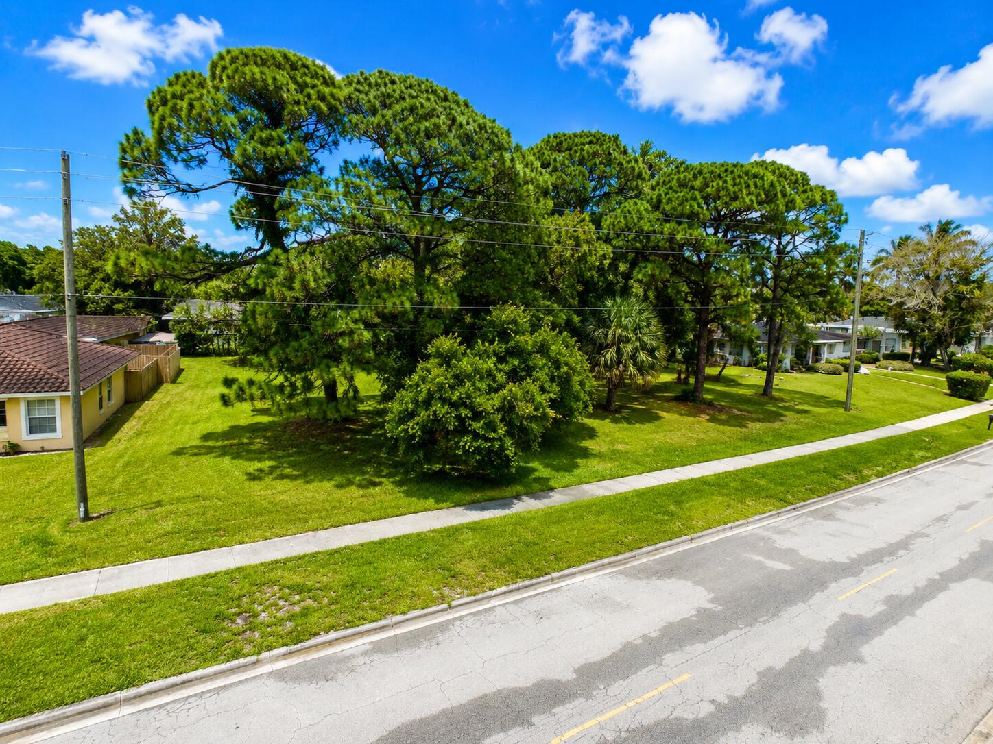 An aerial view shows a grassy lot with several large pine trees beside a road — 1006 Grandview Boulevard, Fort Pierce FL 34982, FORT PIERCE, FL