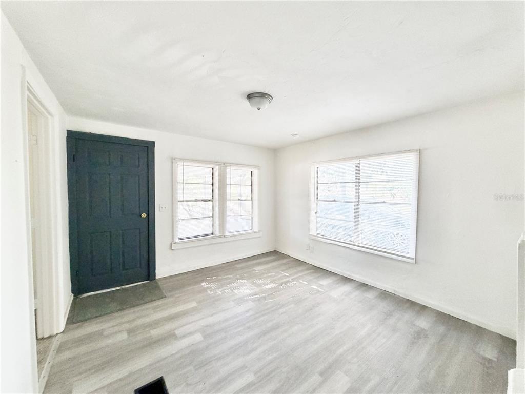 A room with white walls, light wood-look flooring, a dark door, and two windows — 21433 SE HAWTHORNE ROAD, HAWTHORNE, FL