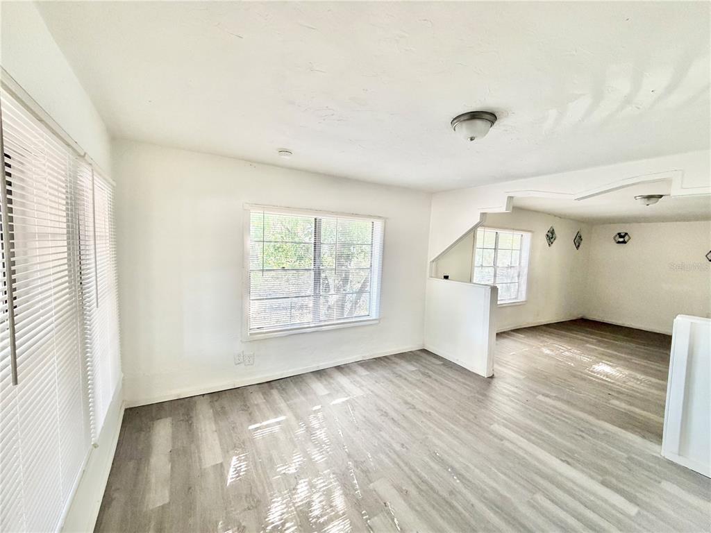 A living area with light wood-look flooring, white walls, and windows with white blinds — 21433 SE HAWTHORNE ROAD, HAWTHORNE, FL