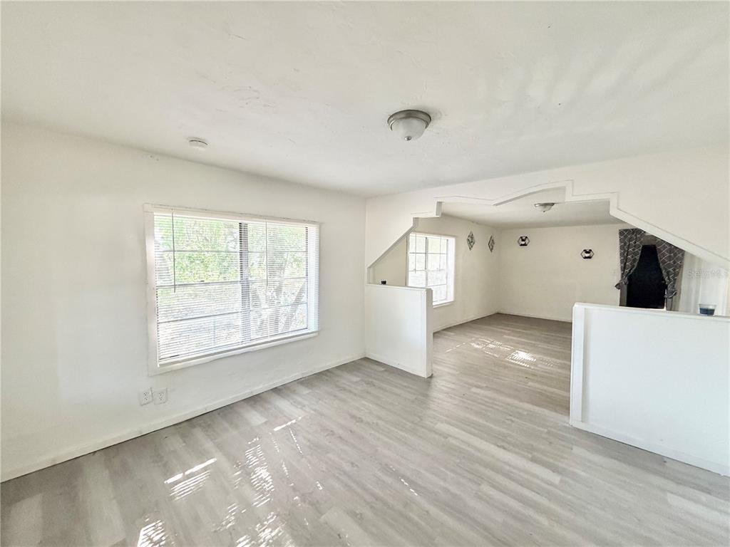 A living room with light wood-look flooring, white walls, and a partial wall divider — 21433 SE HAWTHORNE ROAD, HAWTHORNE, FL
