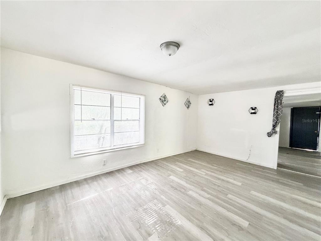 A room with white walls, a window with blinds, and light-colored wood-look flooring — 21433 SE HAWTHORNE ROAD, HAWTHORNE, FL