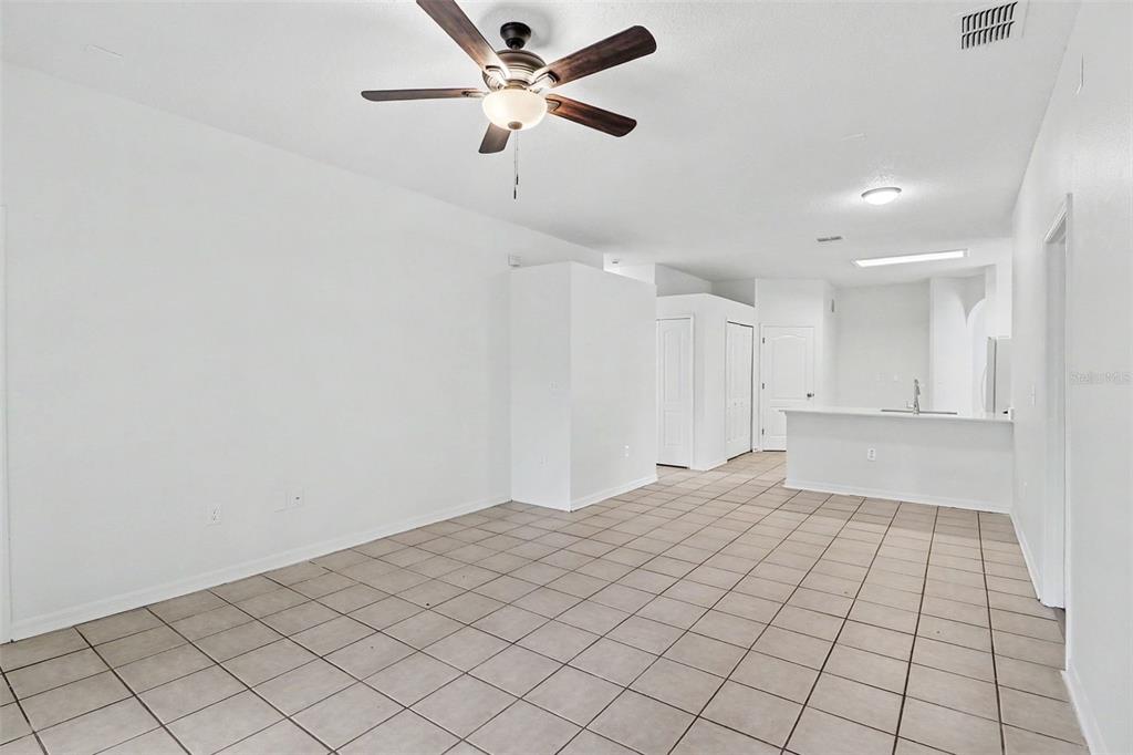 An open-concept living area with white walls, tile flooring, and a ceiling fan — 3709 CINNAMON FERN LOOP, CLERMONT, FL