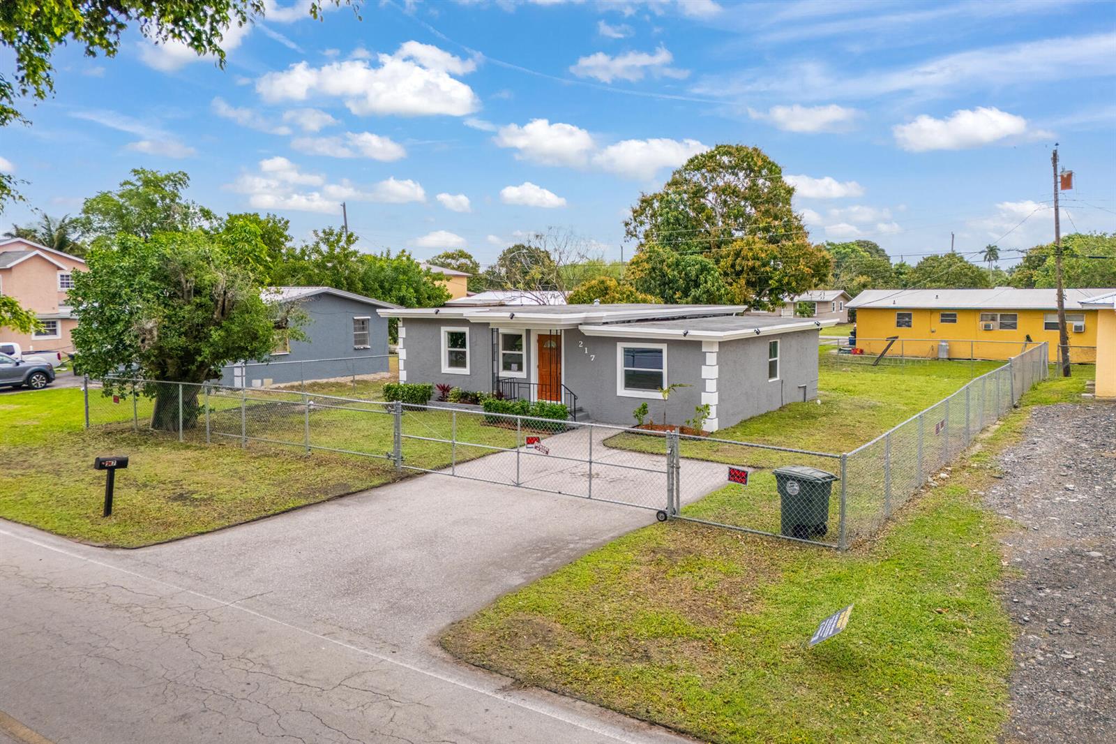 A gray, single-story house with a fenced yard and a concrete driveway — 217 NW 14th Street, Belle Glade FL 33430, BELLE GLADE, FL