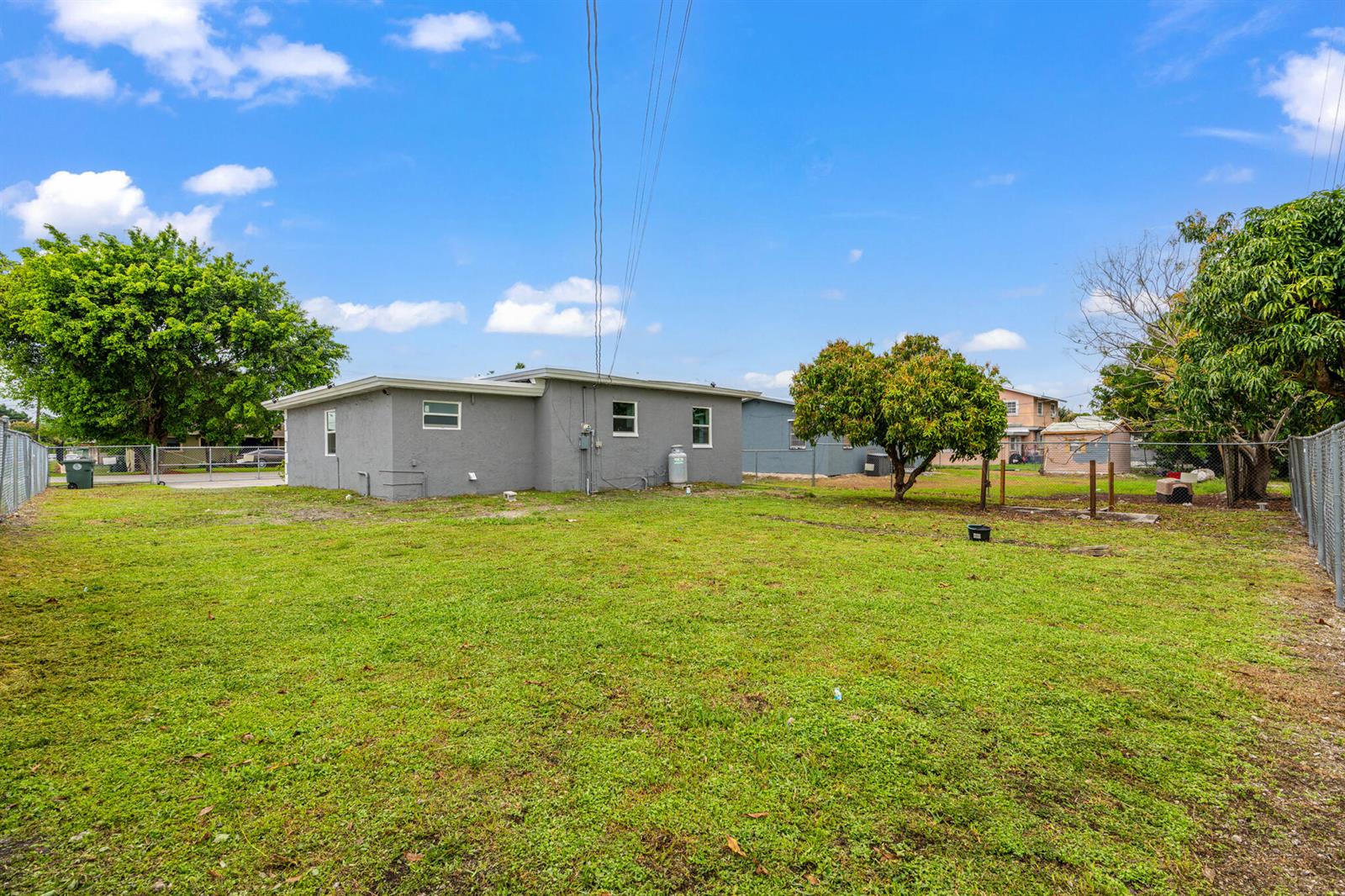 A gray house with a large grassy backyard and a chain-link fence — 217 NW 14th Street, Belle Glade FL 33430, BELLE GLADE, FL