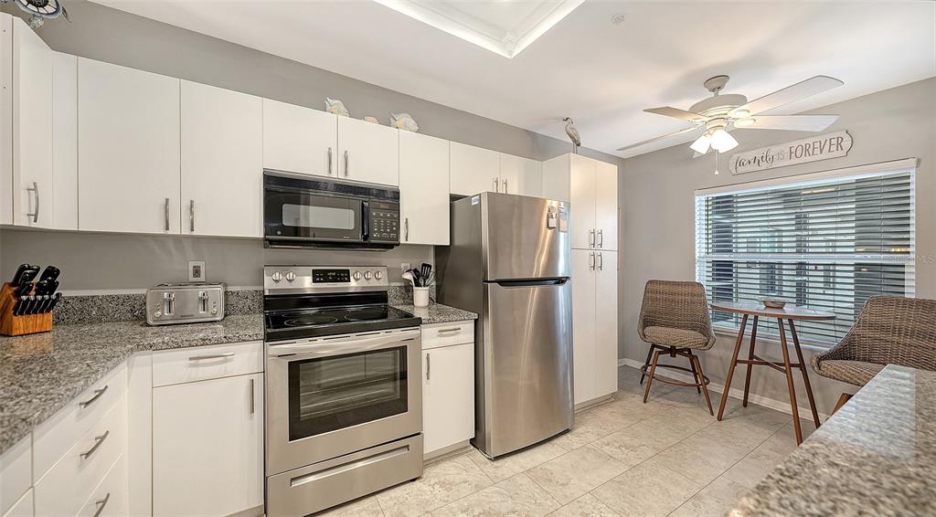 A kitchen features white cabinets, granite countertops, stainless steel appliances, and a small dining area — 9630 CLUB SOUTH CIRCLE UNIT 6202, SARASOTA, FL