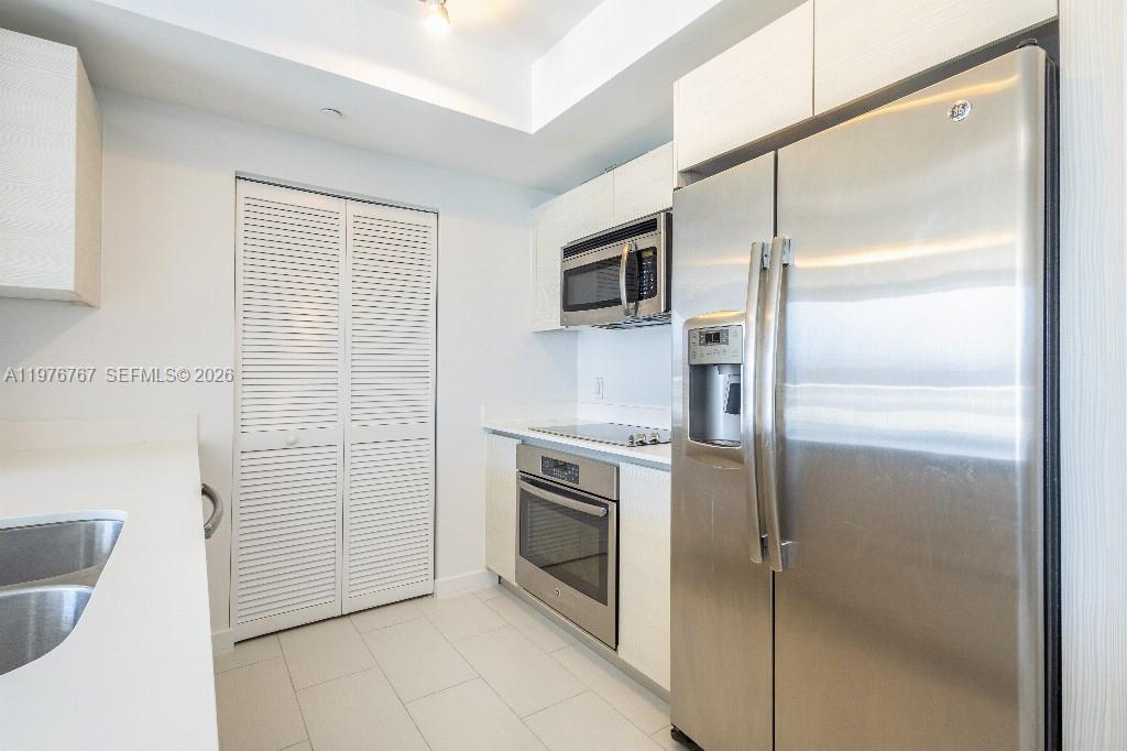 A modern kitchen features stainless steel appliances, white cabinetry, and light-colored tile flooring — 4250 Biscayne Blvd # 816, Miami FL 33137, MIAMI, FL