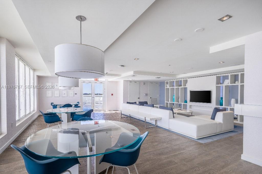 A bright, modern lounge area features glass tables, blue chairs, and a large white sectional sofa — 4250 Biscayne Blvd # 816, Miami FL 33137, MIAMI, FL