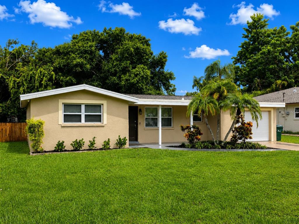 A single-story house with a tan exterior, a white garage door, and a front lawn — 4200 WINTHROP STREET, SARASOTA, FL
