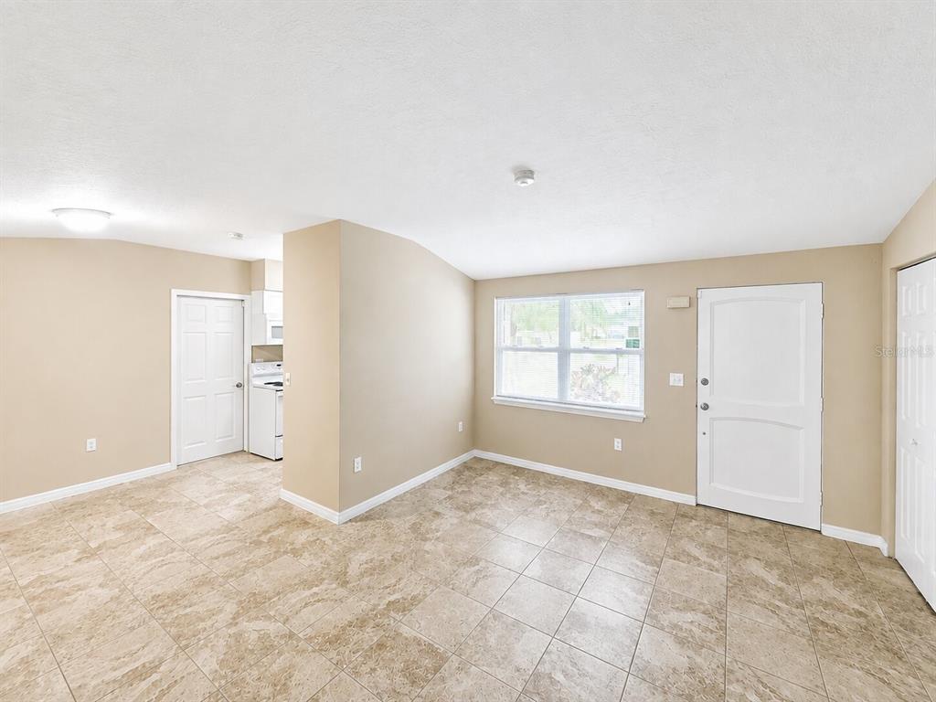 A room with beige walls, tiled floors, a window, and a white entry door — 4200 WINTHROP STREET, SARASOTA, FL