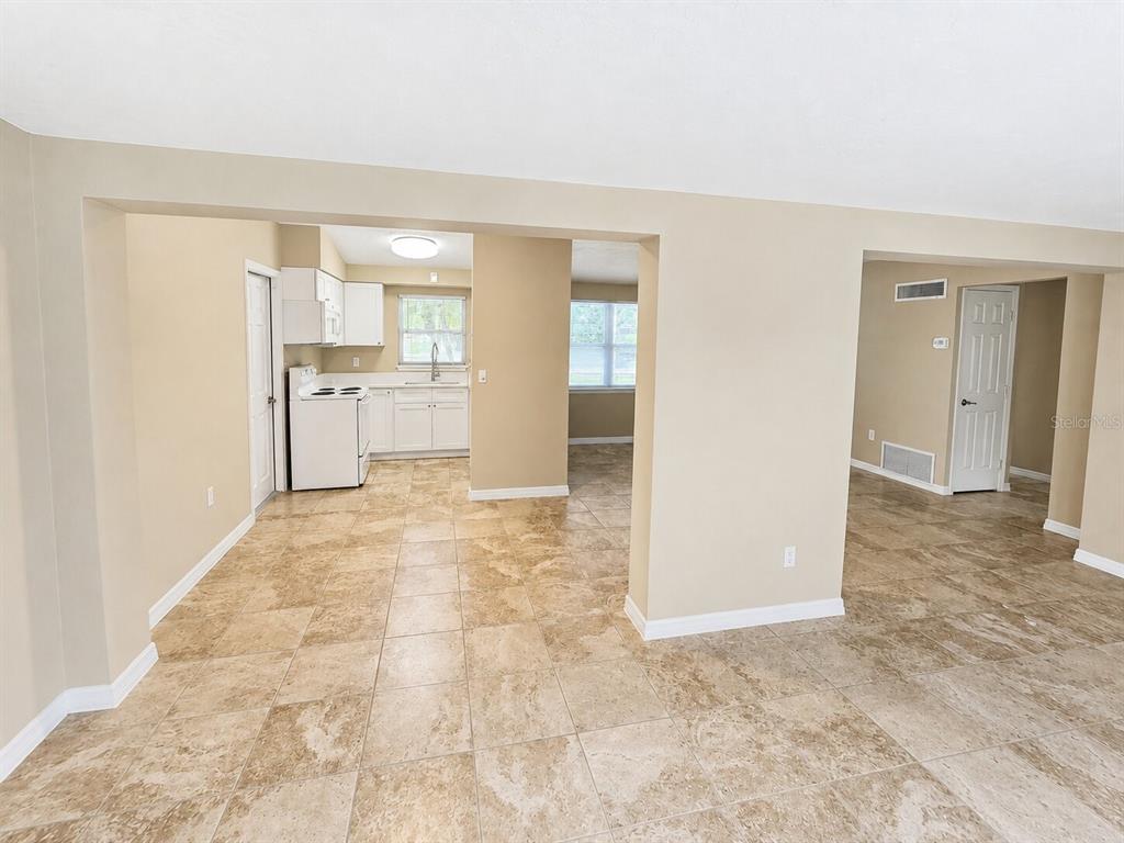 A kitchen with white cabinets and tile flooring opens into an adjacent living area — 4200 WINTHROP STREET, SARASOTA, FL