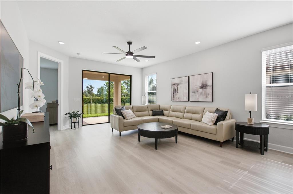 A living room features a beige sectional sofa, a round coffee table, and sliding glass doors — 1369 LOMBARDI COURT, POINCIANA, FL