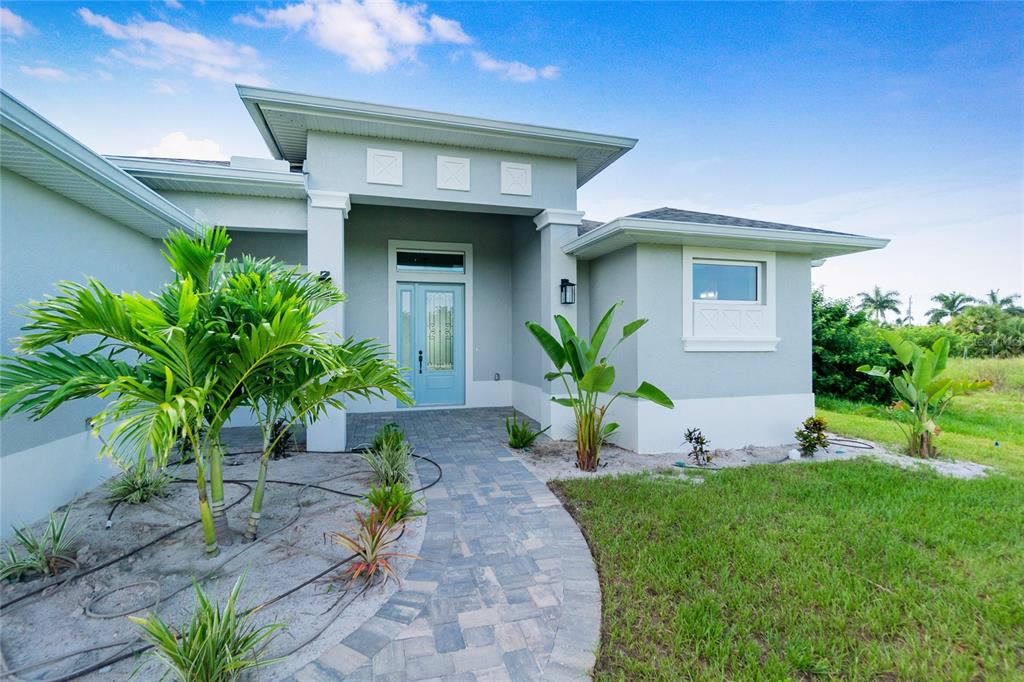 A light blue front door stands at the entrance of a house with gray stucco — 13344 GERSHWIN LANE, PORT CHARLOTTE, FL