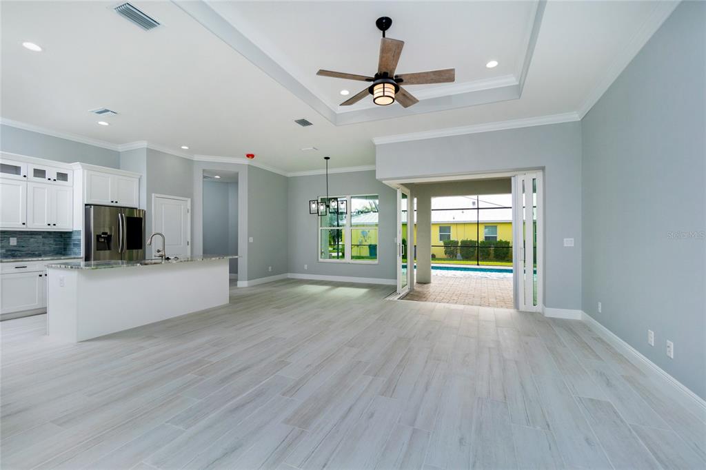 A bright open-concept kitchen and living area with light wood-look tile floors and sliding doors — 13344 GERSHWIN LANE, PORT CHARLOTTE, FL