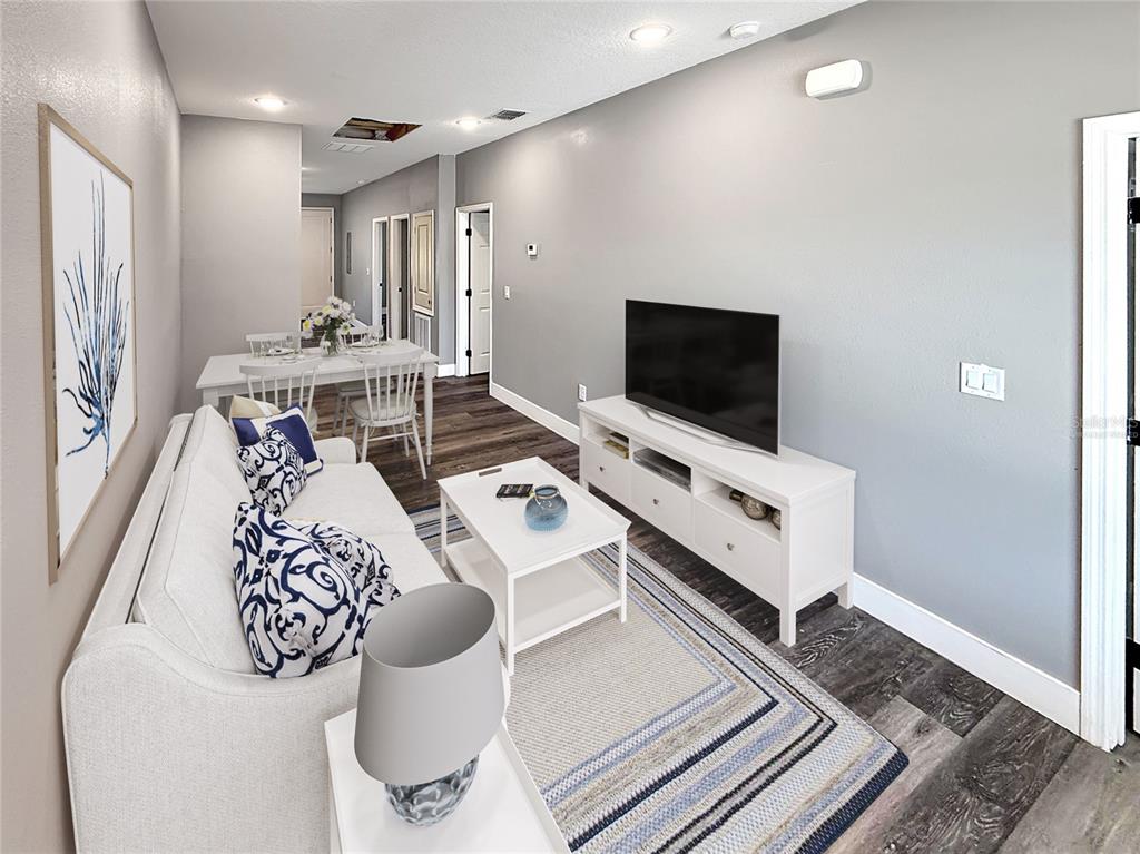A living room with a white sofa, television console, and dining area on wood flooring — 323 PEARL STREET UNIT 1, LAKE WALES, FL