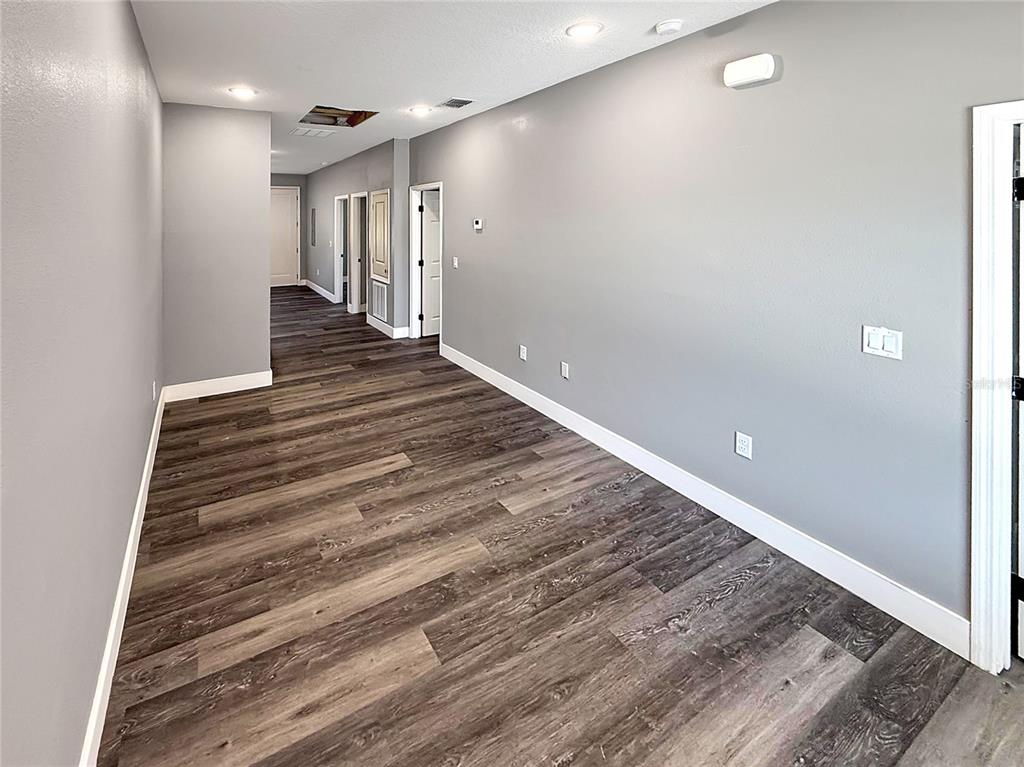 A long, empty hallway features gray walls, white trim, and dark wood-look plank flooring — 323 PEARL STREET UNIT 1, LAKE WALES, FL