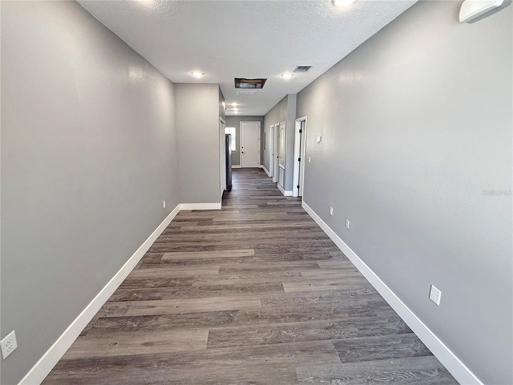 A long, empty hallway features gray walls, white trim, and wood-look plank flooring — 323 PEARL STREET UNIT 1, LAKE WALES, FL