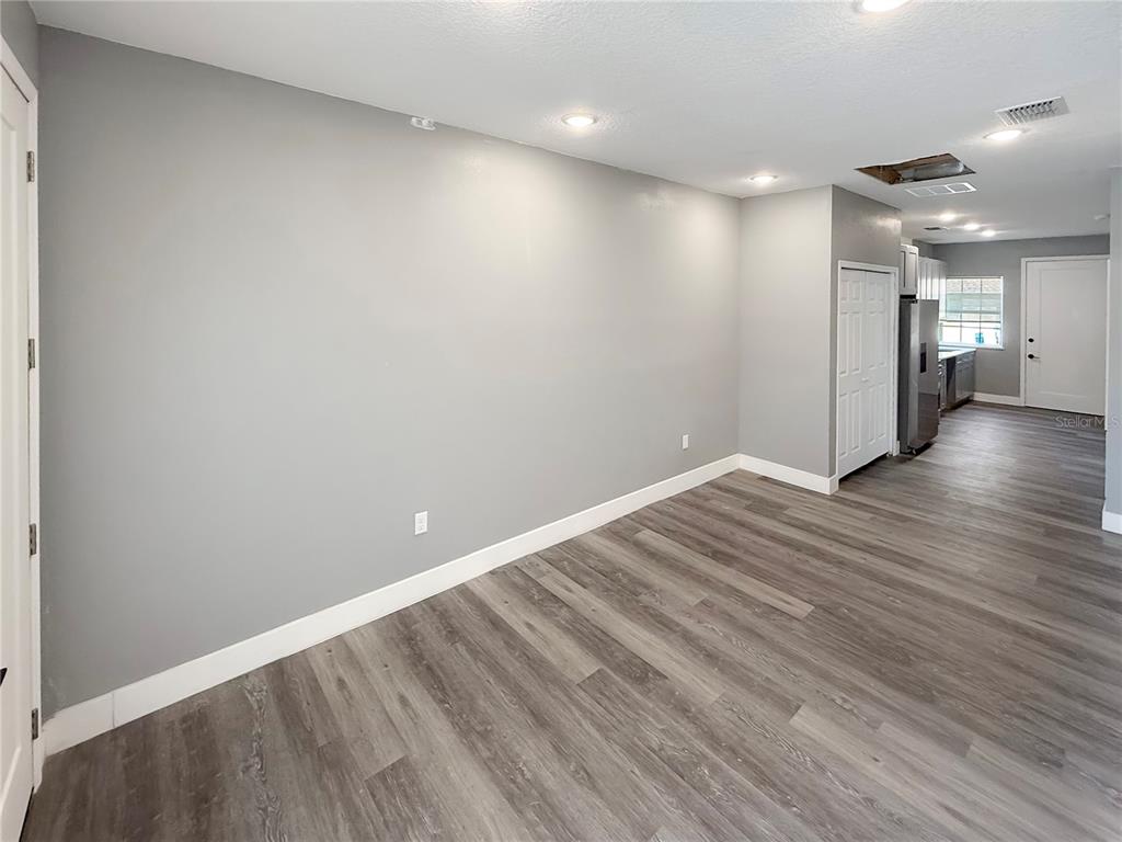 A room with gray walls, wood-look flooring, recessed lighting, and an open view into a kitchen — 323 PEARL STREET UNIT 1, LAKE WALES, FL