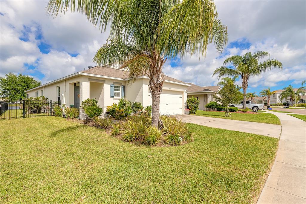 A single-story house with a beige exterior, a two-car garage, and palm trees in front — 554 ARMOYAN WAY, NEW SMYRNA BEACH, FL