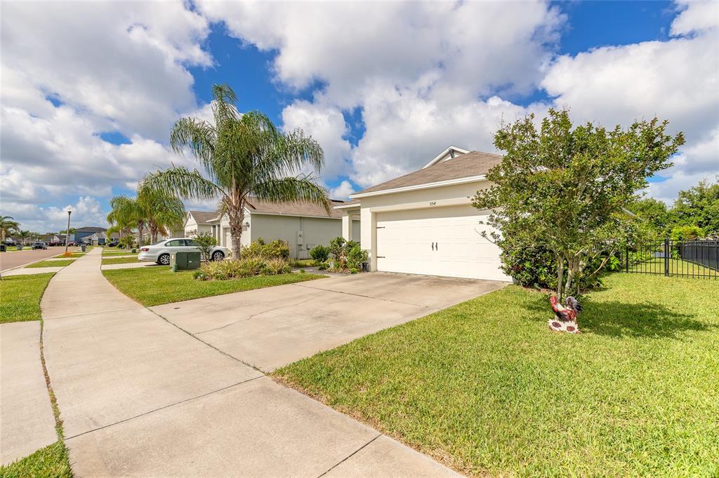 A single-story suburban house features a two-car garage, a concrete driveway, and a palm tree — 554 ARMOYAN WAY, NEW SMYRNA BEACH, FL