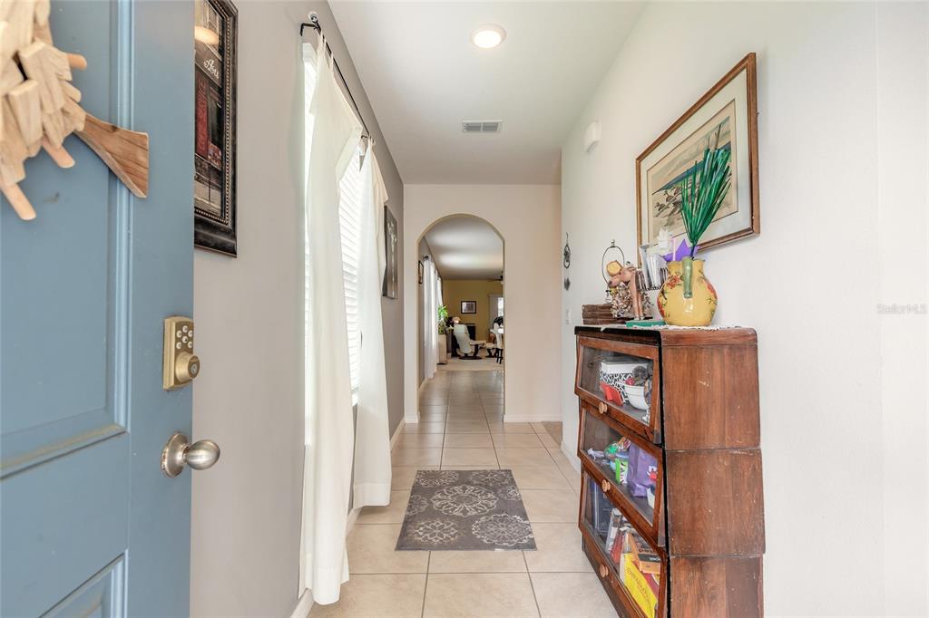 A tiled entryway leads through an arched doorway into a living area with white walls — 554 ARMOYAN WAY, NEW SMYRNA BEACH, FL