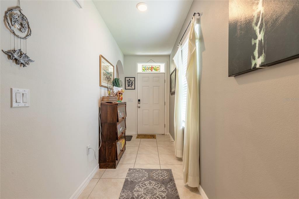 A tiled entryway features a white front door with a transom window and light walls — 554 ARMOYAN WAY, NEW SMYRNA BEACH, FL