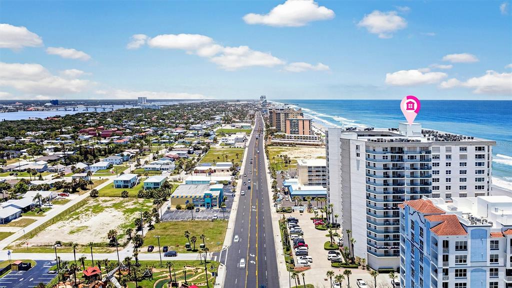 An aerial view shows a coastal road, residential buildings, and a high-rise oceanfront condominium — 2055 S ATLANTIC AVENUE UNIT 603, DAYTONA BEACH, FL