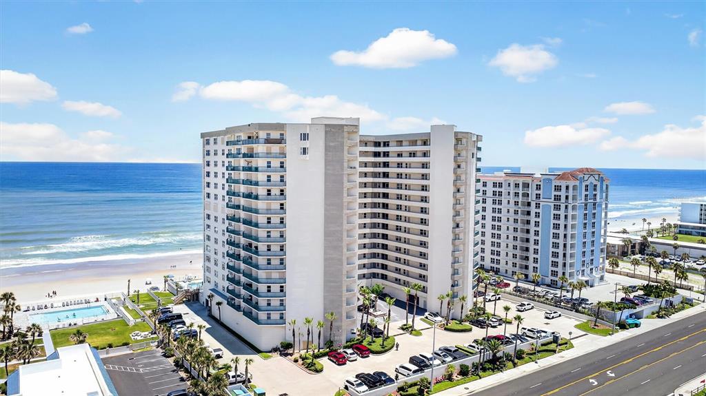 An aerial view shows two large, multi-story beachfront condominium buildings with parking lots and a pool — 2055 S ATLANTIC AVENUE UNIT 603, DAYTONA BEACH, FL