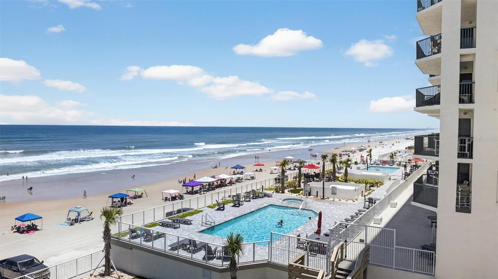 An elevated view shows a beachside swimming pool deck next to a multi-story building — 2055 S ATLANTIC AVENUE UNIT 603, DAYTONA BEACH, FL
