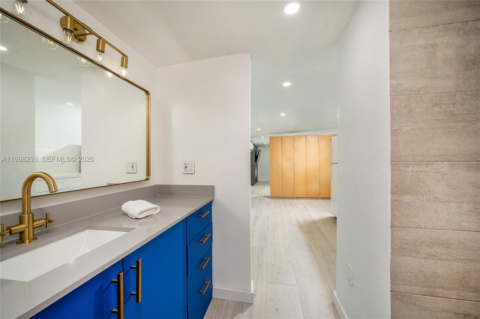 A bathroom vanity with a blue cabinet and gold hardware sits beside a hallway — 10954 SW 157th Ter # 2, Miami FL 33157, MIAMI, FL