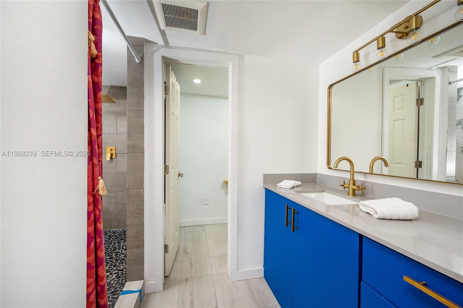 A bathroom features a blue vanity, gold fixtures, a pebble-floor shower, and a separate room — 10954 SW 157th Ter # 2, Miami FL 33157, MIAMI, FL