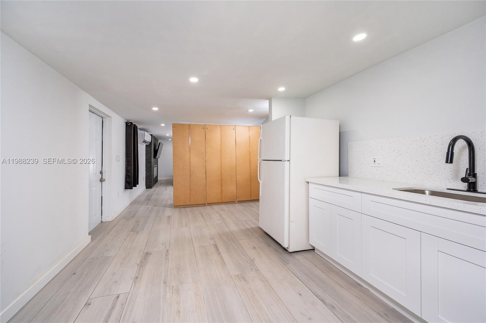 A kitchen area features white cabinets, a white refrigerator, and light wood-look flooring — 10954 SW 157th Ter # 2, Miami FL 33157, MIAMI, FL