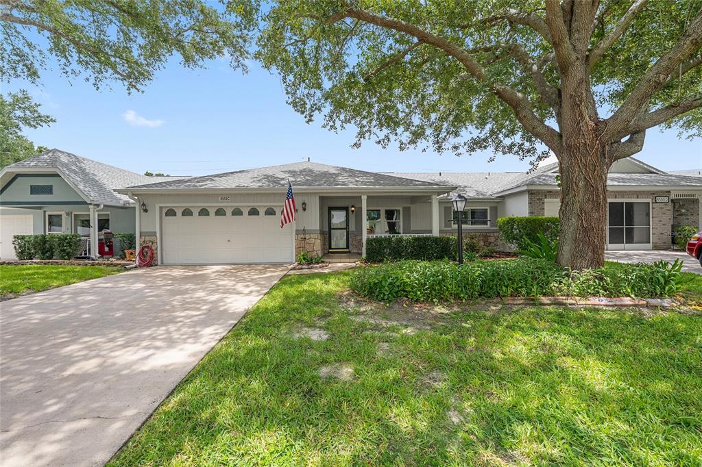 A grassy backyard features a large blooming crape myrtle tree next to a single-story house — 8555 SW 93RD STREET UNIT C, OCALA, FL