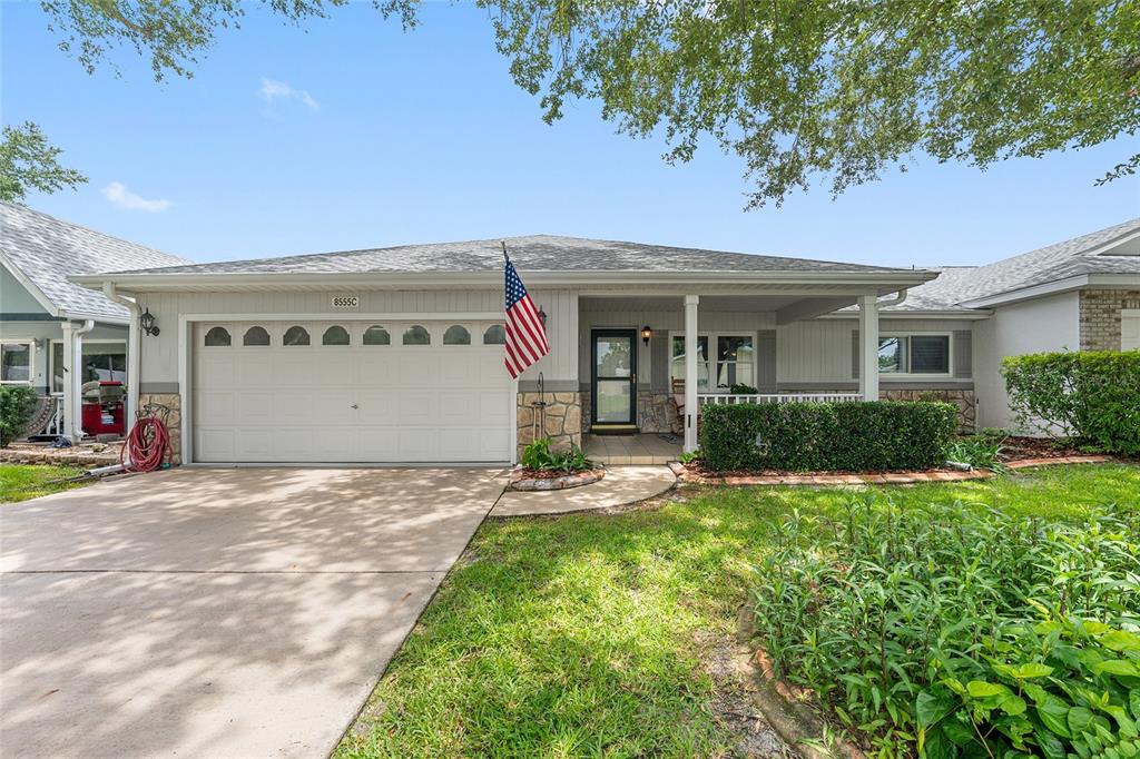A single-story house with a white garage door, stone accents, and an American flag — 8555 SW 93RD STREET UNIT C, OCALA, FL
