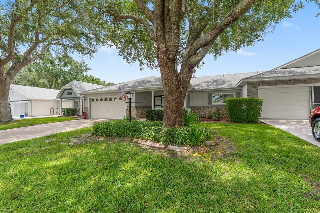A single-story house features a garage, a covered front porch, and a stone facade — 8555 SW 93RD STREET UNIT C, OCALA, FL