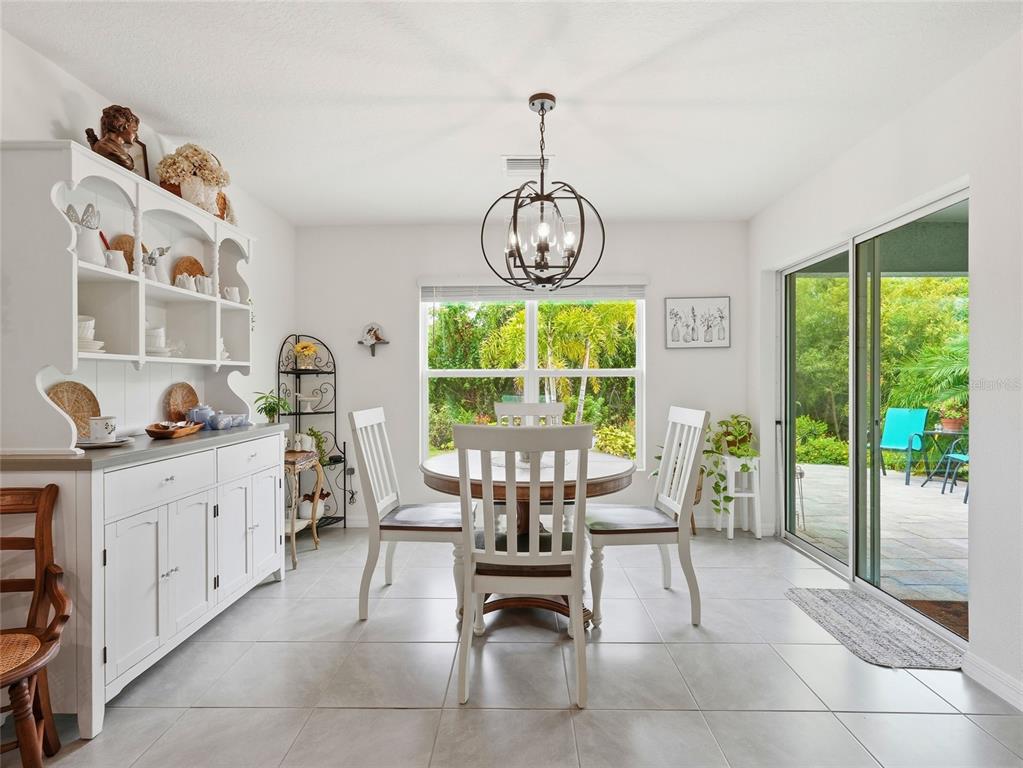 A dining room features a white hutch, a round table with chairs, and sliding glass doors — 4419 HEARTHSTONE RUN, PALMETTO, FL