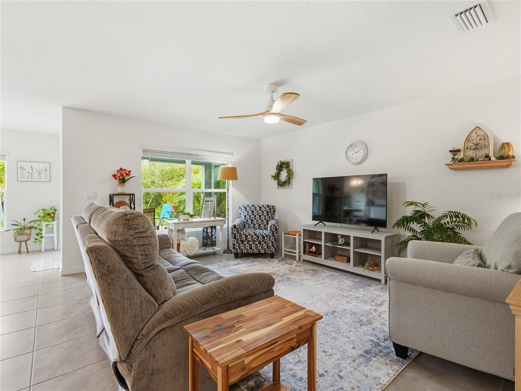 A living room features a sofa, an armchair, a television on a stand, and tile flooring — 4419 HEARTHSTONE RUN, PALMETTO, FL
