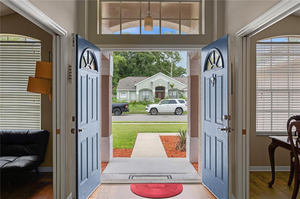 An open double front door reveals a view of a suburban street and neighboring house — 1837 FLORENCE VISTA BOULEVARD, ORLANDO, FL