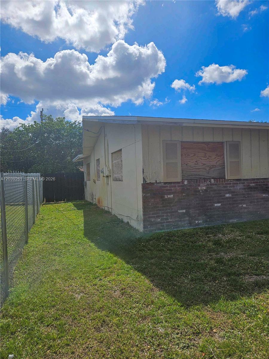 The exterior of a single-story house features boarded-up windows and a brick lower wall — 4506 Taft St, Hollywood FL 33021, HOLLYWOOD, FL