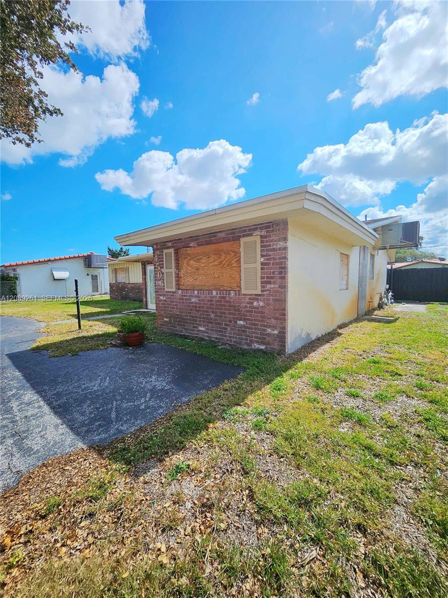 A single-story house with a brick facade, boarded-up window, and a small asphalt driveway — 4506 Taft St, Hollywood FL 33021, HOLLYWOOD, FL
