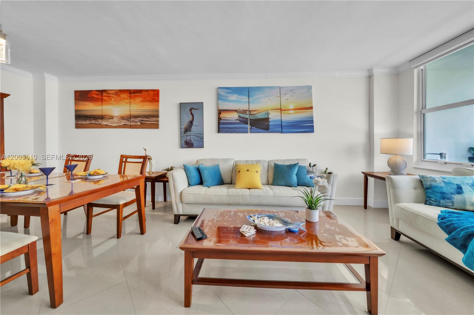 A living and dining room features light tile floors, neutral sofas, and coastal-themed wall art — 3725 S Ocean Dr # 1220, Hollywood FL 33019, HOLLYWOOD, FL