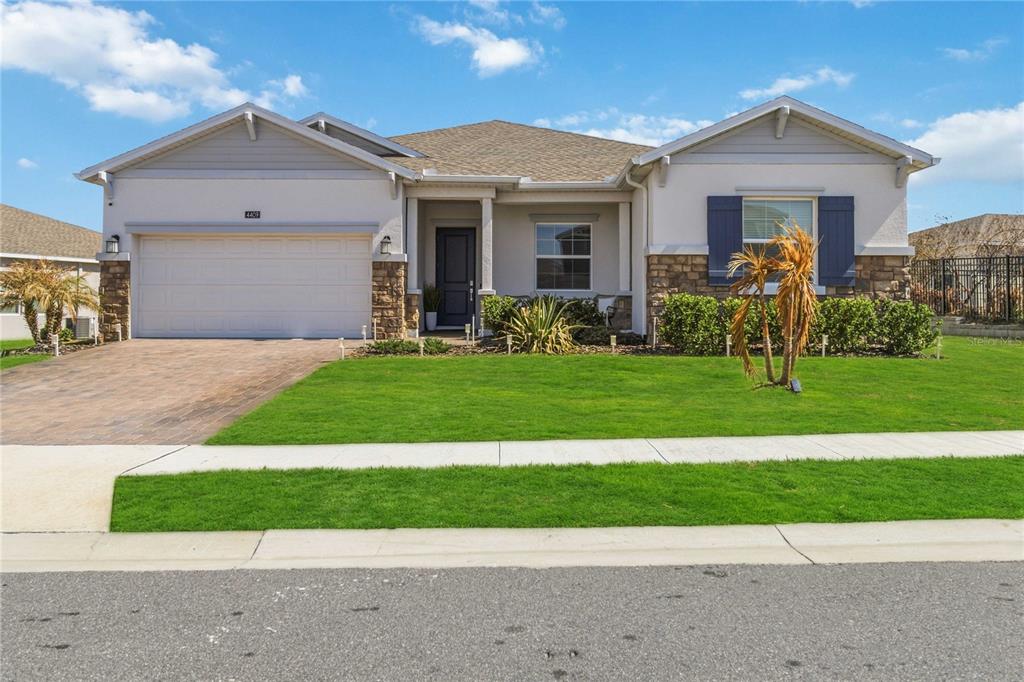 A single-story house with a stone-accented facade, a two-car garage, and a manicured front lawn — 4409 EASTMINSTER ROAD, DAVENPORT, FL
